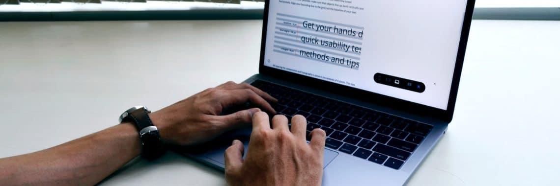 person using macbook pro on white table